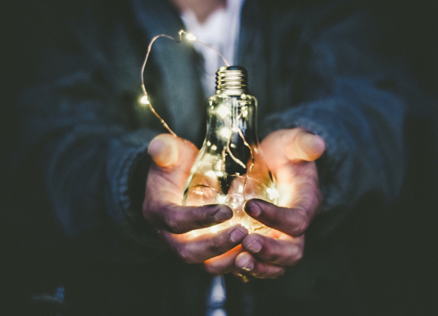 Mannenhanden met lichtpeertje met warm licht